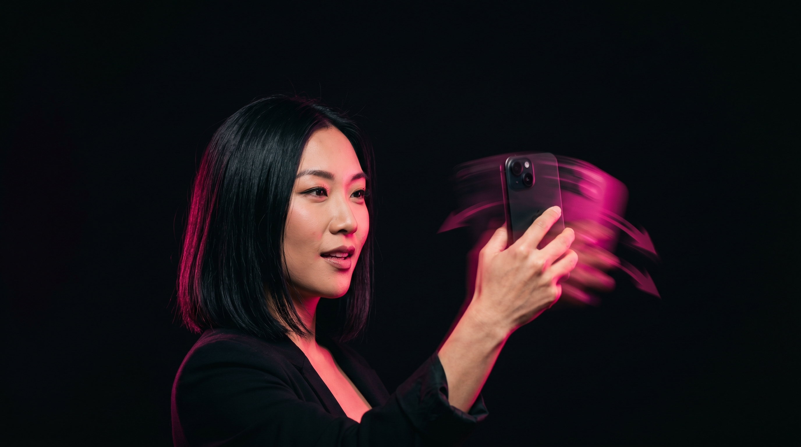 Korean-American woman mid-shake with iPhone trailing hot pink motion blur on a black studio backdrop